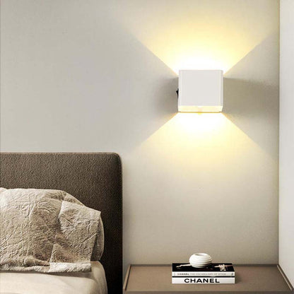 Modern wall light fixture on a neutral wall above a bed with a Chanel book.