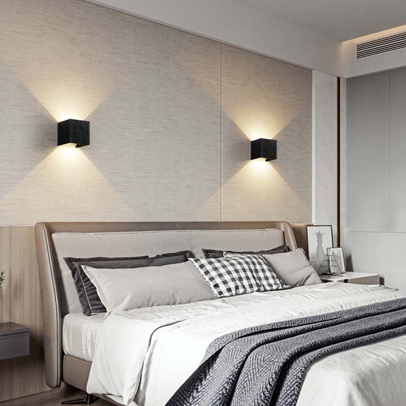 Modern bedroom with a bed, pillows, and wall lights.