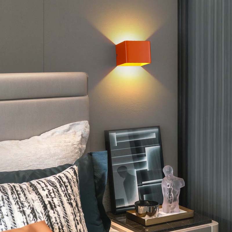 Modern bedroom with a red wall lamp, bed, and decorative items on a nightstand.