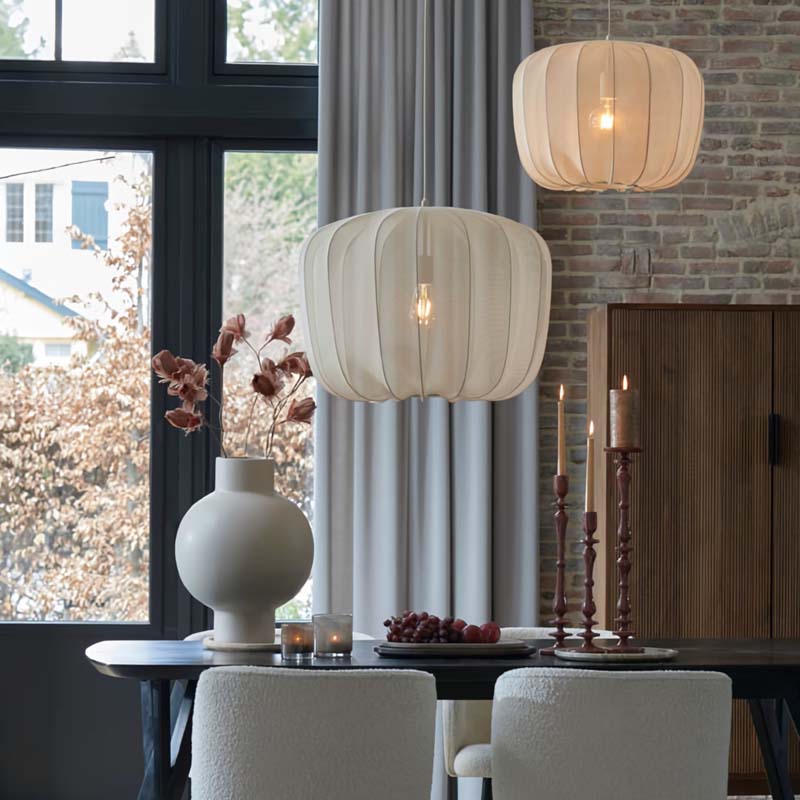 Dining room with white pendant lights, a vase, and candles on a table.