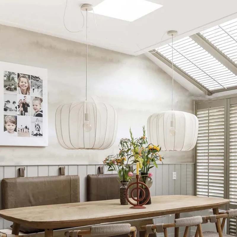 Dining room with wooden table, chairs, and pendant lights.