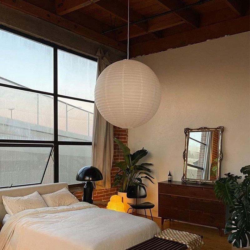 Large white paper pendant lamp hanging above a cozy bedroom interior.