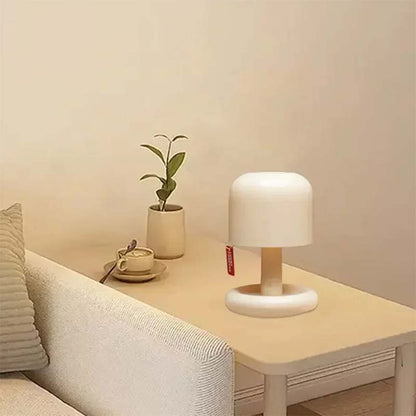 White table lamp on a wooden side table next to a plant and a cup of coffee in a cozy living room.
