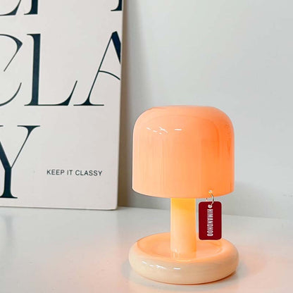 Orange table lamp with a tag on a white surface next to a book titled 'Keep It Classy'.