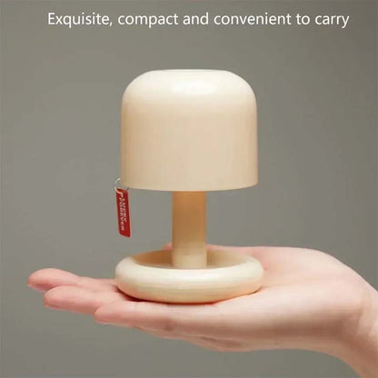 Compact mini mushroom bedside lamp resting in the palm of a hand, highlighting its portable size, lightweight design, and soft ambient lighting for bedrooms, travel, or cozy spaces