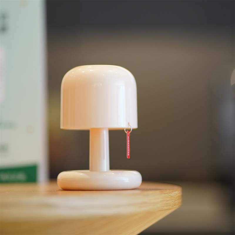 Small white lamp with a wooden base on a surface, blurred background