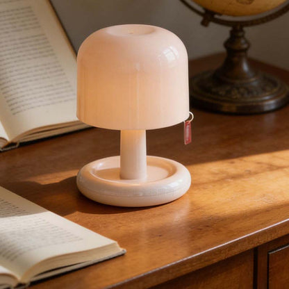 Small white lamp on a wooden surface with books and a globe in the background