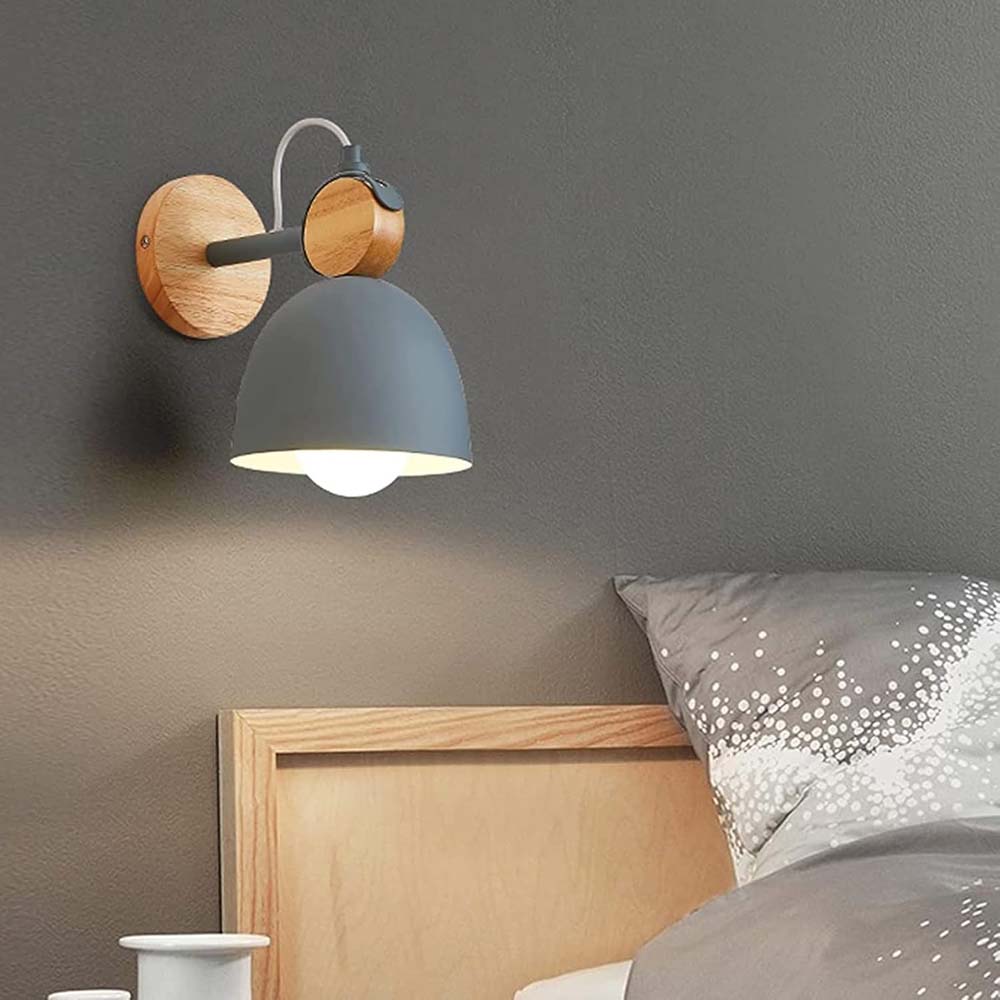 Wall-mounted lamp with wooden base and gray shade in a bedroom setting.