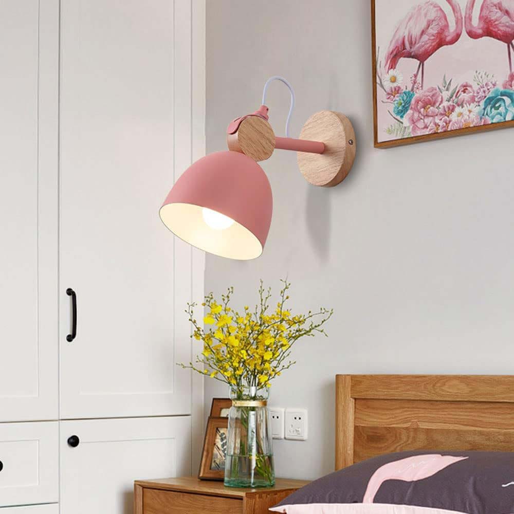 Pink wall lamp in a bedroom setting with a wooden headboard and yellow flowers.