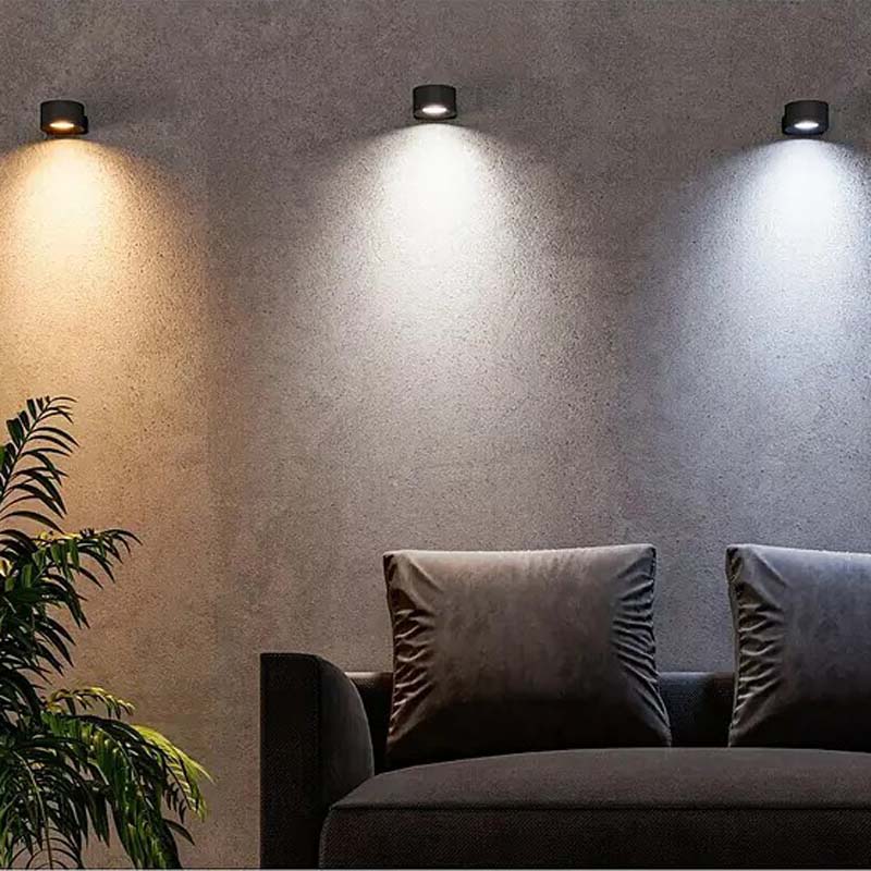 Wall lights illuminating a room with a couch and plant