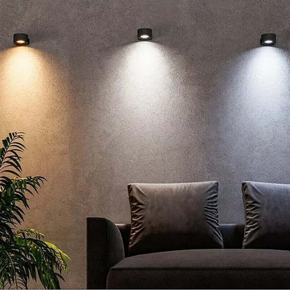 Wall lights illuminating a room with a couch and plant