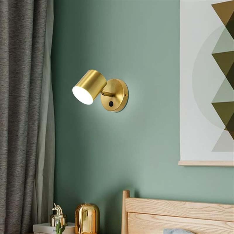 Gold wall sconce on a green wall with a geometric painting in the background