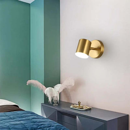 Gold wall sconce on a white wall with teal accent wall and decorative items.