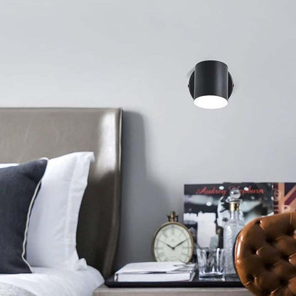 Black ceiling light fixture on a gray wall above a bed with decorative items.