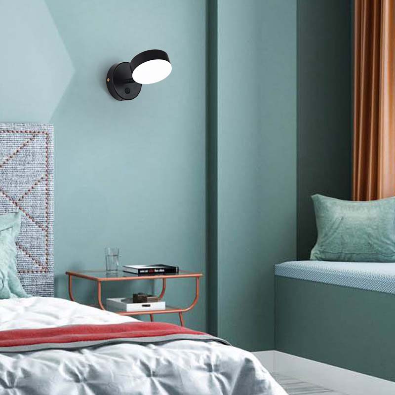 Modern bedroom with a wall-mounted light fixture, bed, and side table.