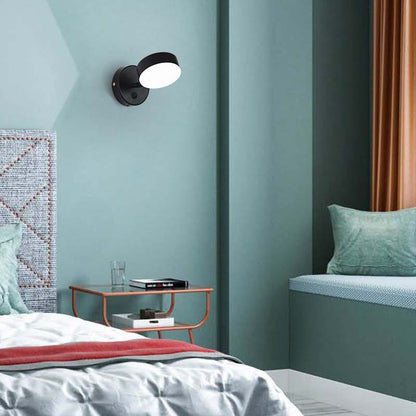 Modern bedroom with a wall-mounted light fixture, bed, and side table.