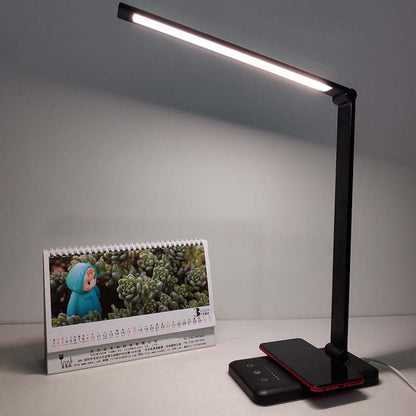 Black LED desk lamp on a surface with a calendar and smartphone in the background.