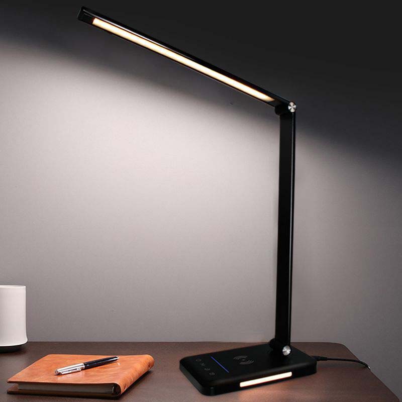 Black LED desk lamp on a wooden surface with a notebook and pen in the background.