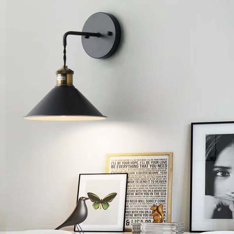 Black wall sconce light fixture on a white wall with framed pictures below.