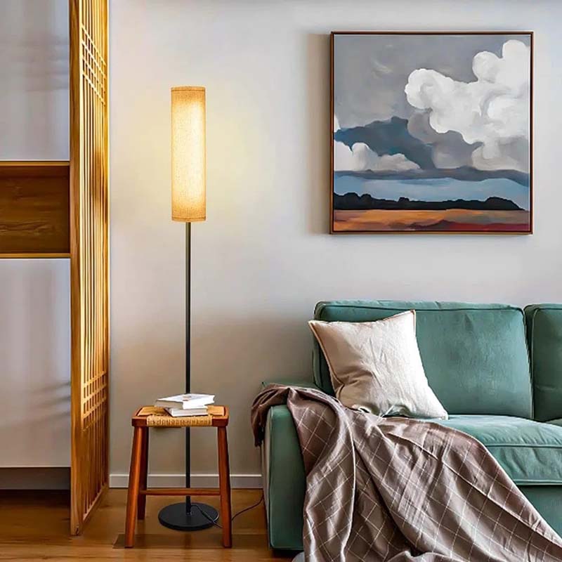 Living room with teal sofa, wooden floor lamp, and abstract painting on wall.