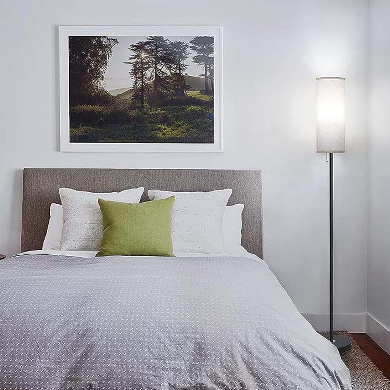 Bedroom with a bed featuring white and green bedding, a lamp, and a framed picture on the wall.