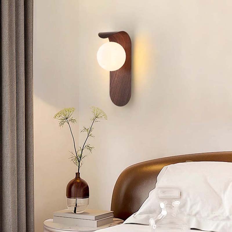 Wall-mounted lamp and vase with flowers on a nightstand in a bedroom setting.
