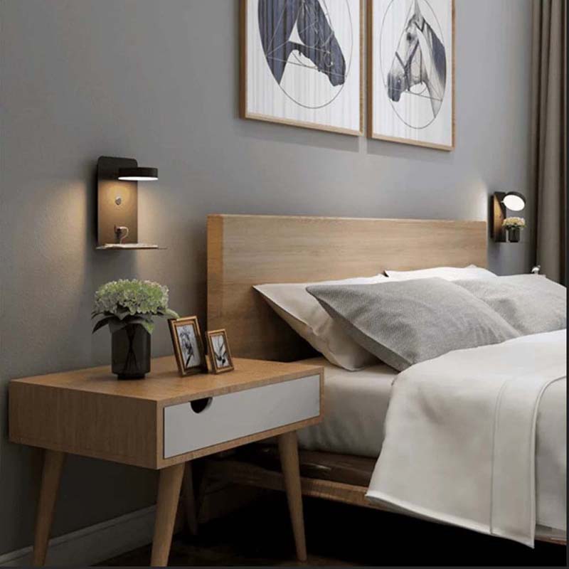 Modern bedroom with wooden bed and side table, featuring wall art and lighting.