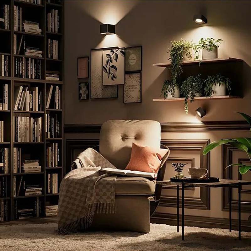 Touch LED Wall Sconce in the interior of a cozy living room with a bookshelf, an armchair and decorative elements.