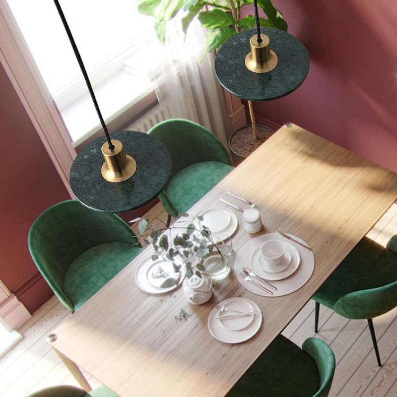 Modern Marble Pendant Light in a dining area with a wooden table set for dining and green chairs.