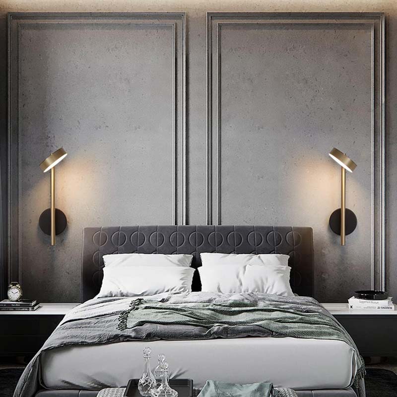 Modern bedroom with gray upholstered headboard, wall lamps, and decorative pillows.