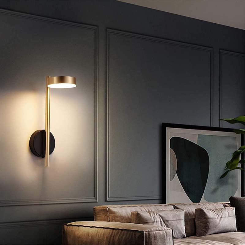 Modern wall sconce on a dark gray wall with a sofa and abstract art in the background