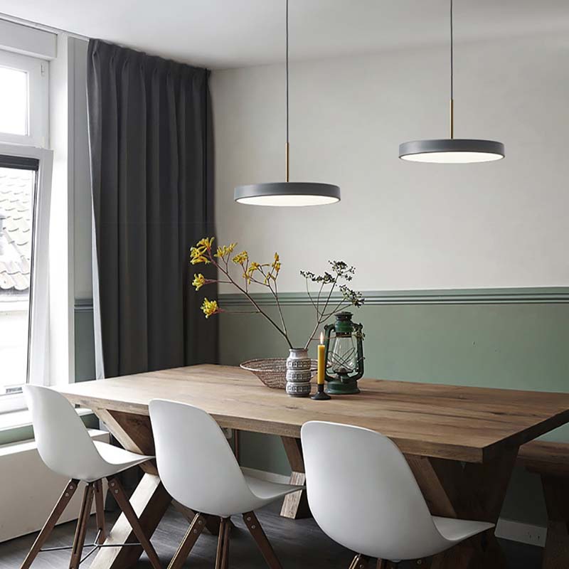 Dining area with a wooden table and white chairs, featuring pendant lights and a window.