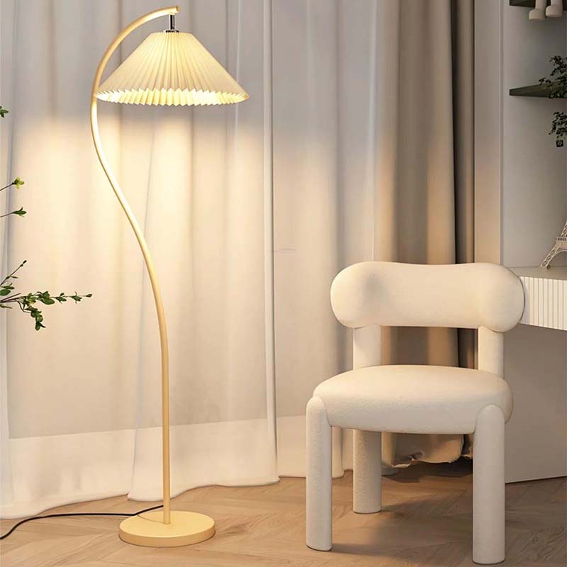 Modern floor lamp with a white shade next to a white chair in a room with light-colored curtains.