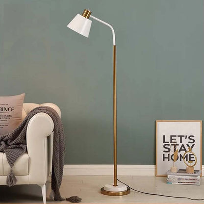 Modern floor lamp with white shade and gold base in a living room setting.