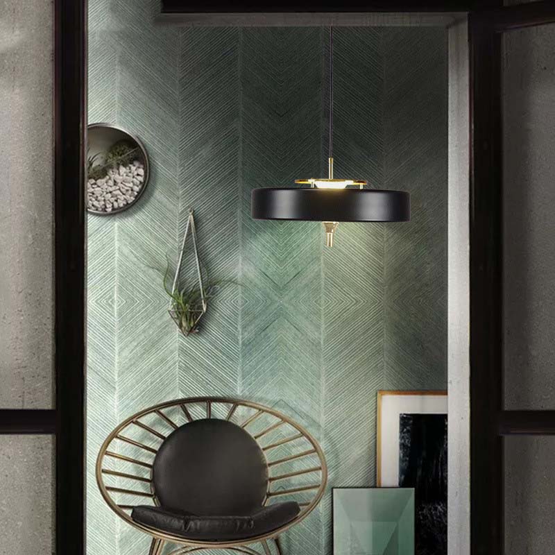 Modern interior with a black pendant light, green textured wall, and a black chair.