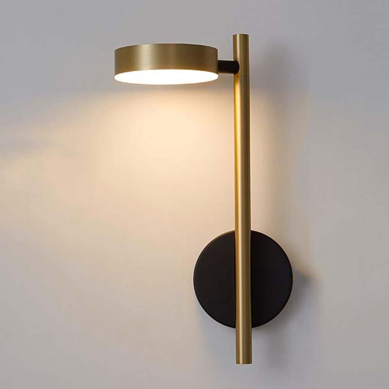 Modern wall lamp with gold finish and black base on a gray wall