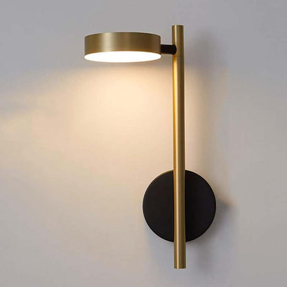 Modern wall lamp with gold finish and black base on a gray wall