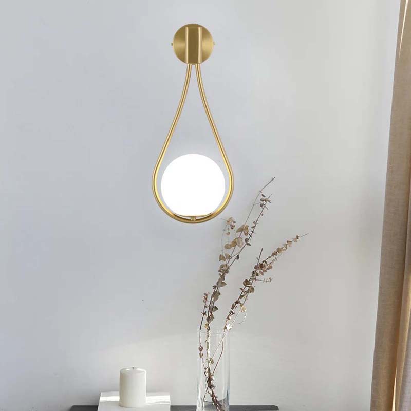 Modern wall-mounted light fixture with gold finish on a neutral background