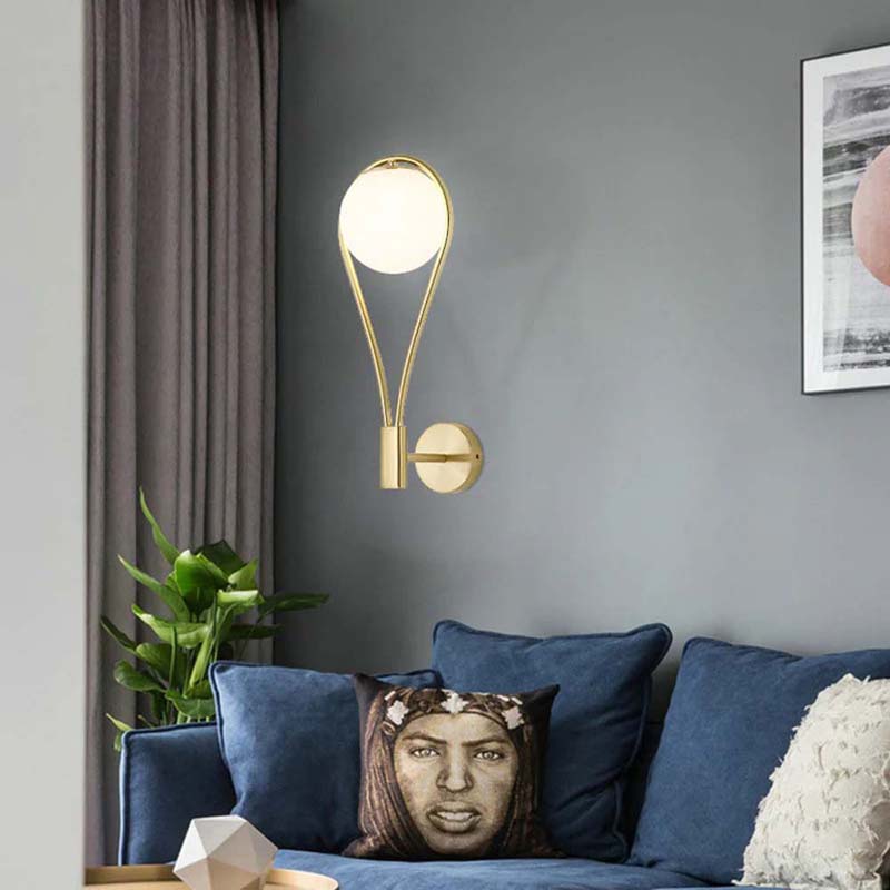 Modern wall lamp on a gray wall above a sofa with decorative pillows.