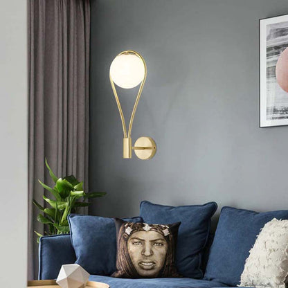 Modern wall lamp on a gray wall above a sofa with decorative pillows.