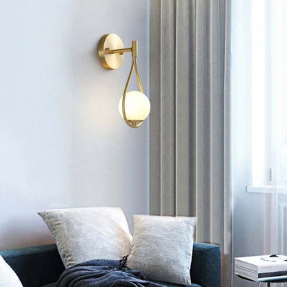 Modern wall lamp with a spherical bulb on a light gray wall in a living room.