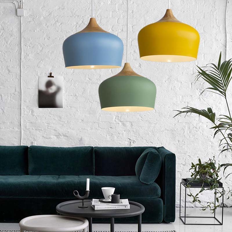 Three colorful pendant lights hanging above a dark green sofa in a modern living room.
