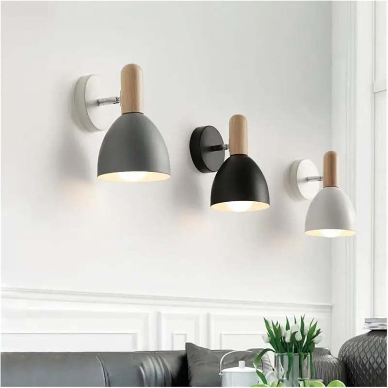 Three wall-mounted lamps with different shades of gray and wooden accents on a white wall.