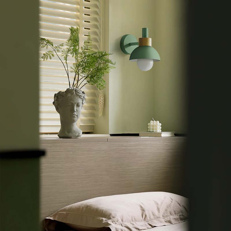 Decorative wall lamp with a plant and sculpture on a shelf in a room.