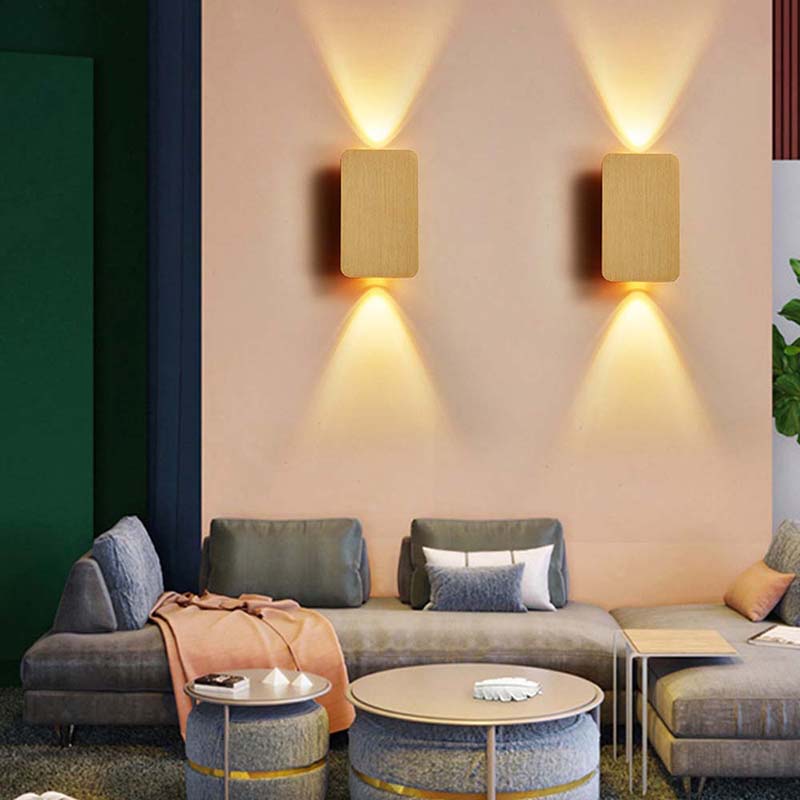 Modern living room with a gray sofa, decorative pillows, and wall-mounted lights.