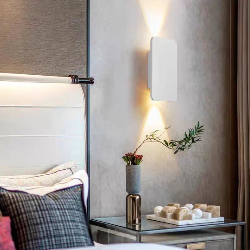 Modern wall sconce in a bedroom setting with a bed and decorative items.