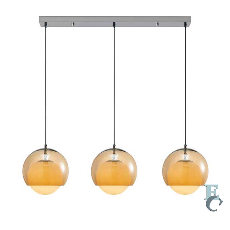 Three pendant lights with amber glass shades hanging from a silver fixture.