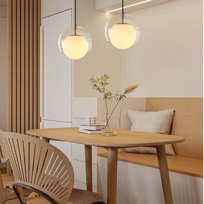 Pendant Globe Light in a dining area with a wooden table, chairs and bench against a neutral wall.