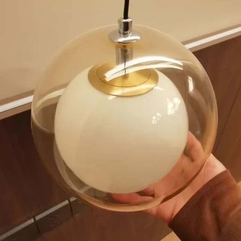 Pendant light with a glass cover held by a person against a neutral background