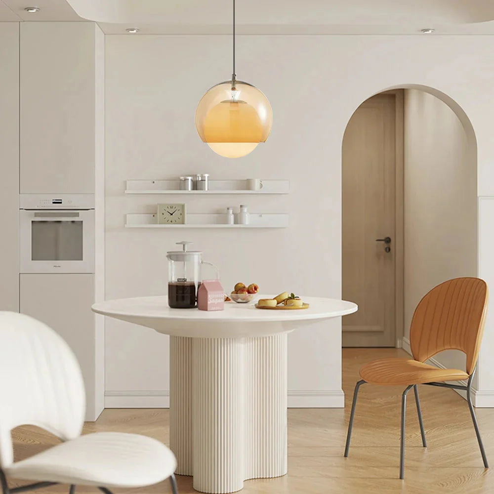 Pendant Globe Light in a modern kitchen with a round white table and wooden chairs.